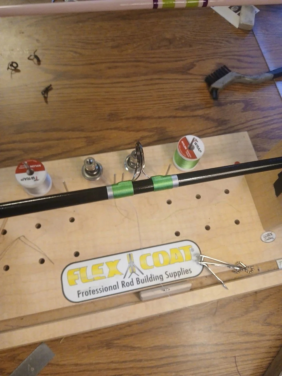 Green guide wrapping, thread spools, and tools on the BDRX Customs rod-building bench.